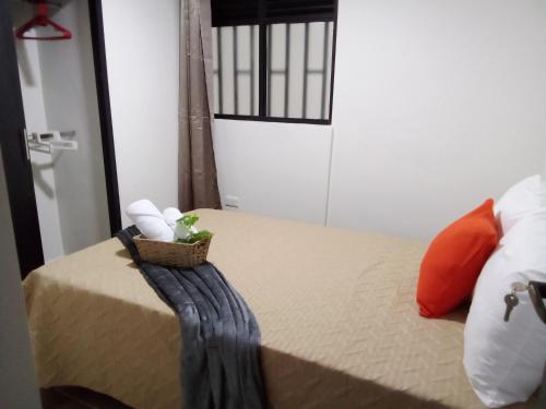 een slaapkamer met een bed en een mand met handdoeken bij Los Cauces familiar y central in Medellín