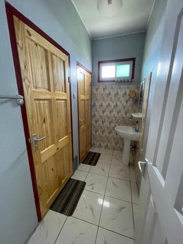 a bathroom with a wooden door and a sink at Zeedijk Resort Nickerie in Nieuw Nickerie
