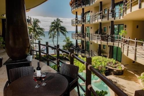 a table with wine glasses on a balcony with a view of the ocean at El Taj Oceanfront and Beachside Condo Hotel in Playa del Carmen