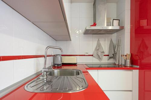 a red and white kitchen with a sink at Bonito, Práctico y muy bien comunicado in Madrid