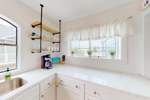 a white kitchen with a sink and a window at A Pirate's Paradise in Galveston
