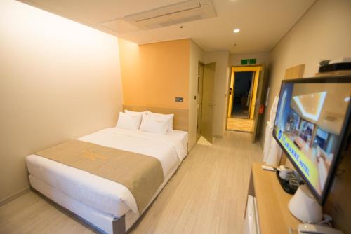 a hotel room with a bed and a flat screen tv at Haeundae Marianne Hotel in Busan