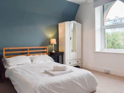 1 dormitorio con 1 cama blanca grande y ventana en Chambercombe Villa - Harbour View, Decking, Garden, Games Room, sleeps 20, en Ilfracombe