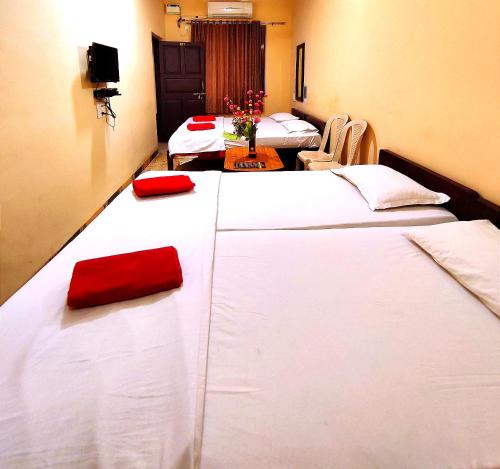 a room with four beds with red pillows on them at Mandarin Hotel Mapusa in Mapusa
