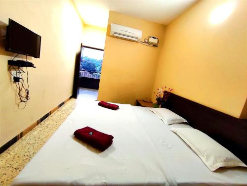 a bedroom with a white bed with a red bag on it at Mandarin Hotel Mapusa in Mapusa