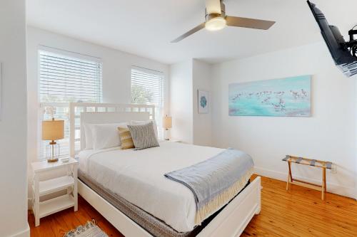 a white bedroom with a bed and a ceiling fan at Mapacebo in Port Aransas