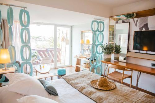 een slaapkamer met een bed, een bureau en een televisie bij Relais et Châteaux Thalasso & Spa Ile de la Lagune in Saint-Cyprien