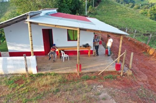 een klein huis met een veranda en mensen buiten bij Ecohotel Casa de Descanso La Pradera in Confines