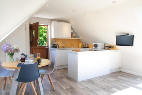 cocina con encimera y mesa con sillas en The Roost - a bird's eye view in the countryside en Cullompton