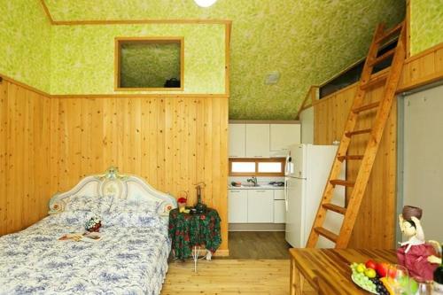 a bedroom with a bed and a ladder and a kitchen at Matryoshka Pension in Ulsan