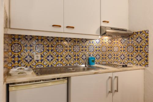 a kitchen with a sink and a tiled wall at Apartamentos Pescadores in Albufeira