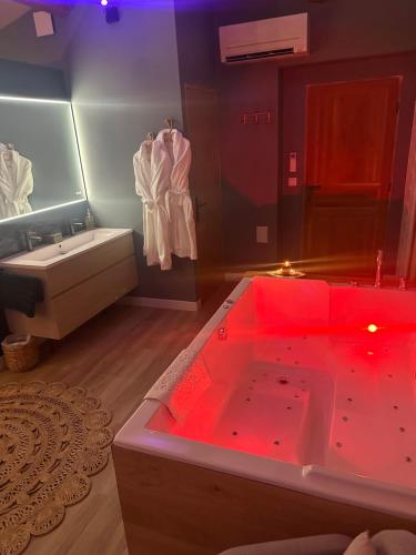 La salle de bains est pourvue d'une grande baignoire avec éclairage rouge. dans l'établissement Mas Hinaiti - Suite romantique avec Spa et écran géant de cinéma, à Montpellier