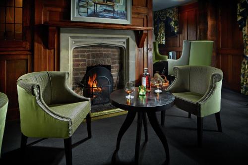 a living room with a fireplace and a table and chairs at Langshott Manor - Luxury Hotel Gatwick in Horley