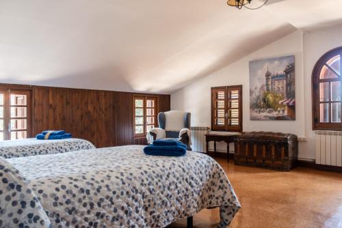 a bedroom with two beds and a chair at Dehesa Vieja Casa Rural in Alarcón