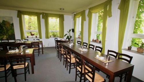 una sala da pranzo con tavoli, sedie e finestre di Pension Zur Fledermaus a Waren