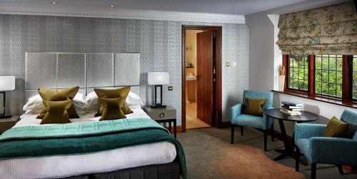 a bedroom with a bed and two chairs and a table at Langshott Manor - Luxury Hotel Gatwick in Horley