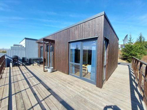 una casa de madera con puertas de cristal en una terraza en Giljagisting en Grafarkirkja