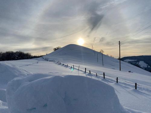 a snow covered slope with the sun in the background at "La Casa dei Gelsi" - Panorama Lodge MONTE GENEROSO in Scudellate