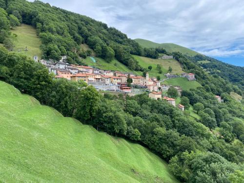 a village on the side of a green hill at "La Casa dei Gelsi" - Panorama Lodge MONTE GENEROSO in Scudellate