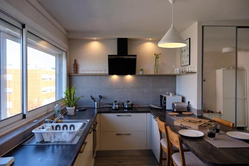 une cuisine avec un évier et une table avec des chaises dans l'établissement Two bedrooms modern apartment close to Tram, à Toulouse