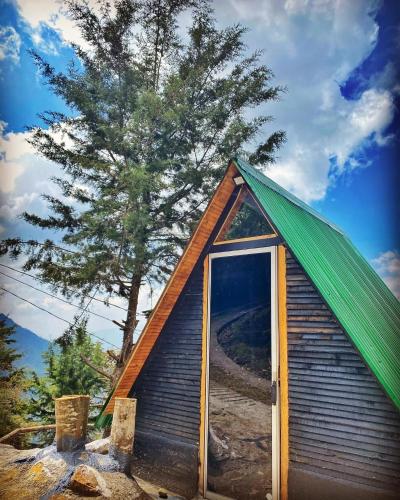 a small house with a green roof and a tree at Encantador Glamping Alaska in Medellín
