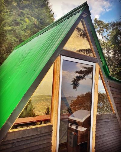 a house with a green roof with a large window at Encantador Glamping Alaska in Medellín