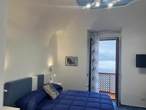 a bedroom with a blue bed and a balcony at Amalfi Sea View in Scala