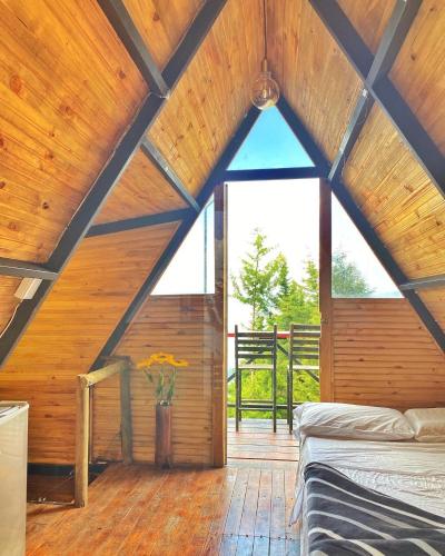 a attic room with a bed and a large window at Encantador Glamping Alaska in Medellín