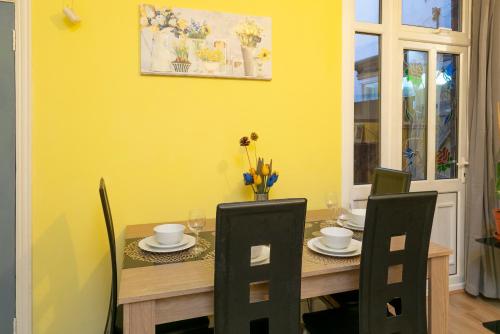 a dining room table with chairs and a yellow wall at SPS Homes in Birmingham