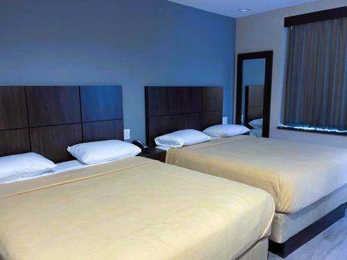 2 Betten in einem Hotelzimmer mit blauen Wänden in der Unterkunft Royal Hotel Bronx in Bronx