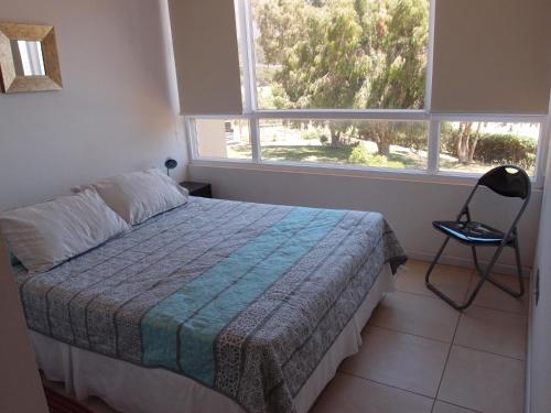 a bedroom with a bed and a chair and a window at Acogedor Departamento en tranquilo balneario, Papudo in Papudo