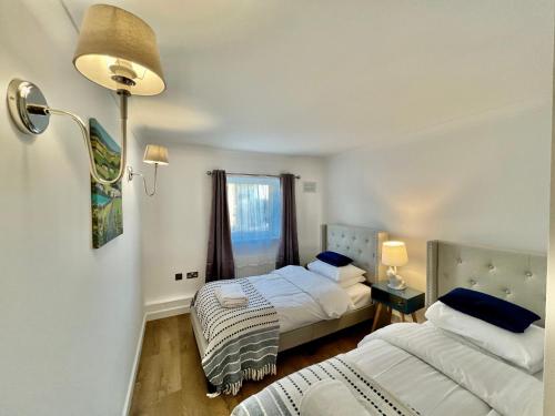 a bedroom with two beds and a lamp and a window at Kiwi Tree Serviced Apartment in Cambridge