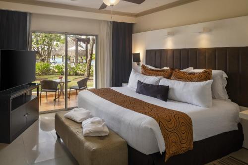 um quarto de hotel com uma cama grande e uma televisão em Jewel Palm Beach em Punta Cana