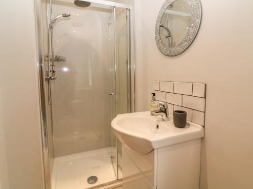 a white bathroom with a sink and a shower at Cae Glas in Pwllheli