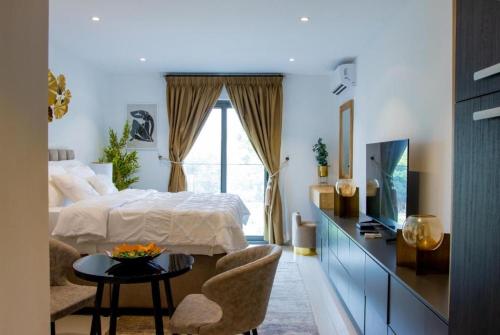 Schlafzimmer mit einem Bett, einem TV und einem Tisch in der Unterkunft Splendid Apartments @ The Lennox in Accra