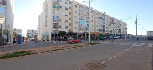eine Straße mit einem Gebäude und einem roten Auto auf der Straße in der Unterkunft Darna in Agadir