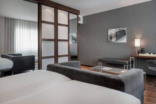 サン・セバスティアン・デ・ロス・レイエスにあるAC Hotel San Sebastián de los Reyes by Marriottのベッドとリビングルームが備わるホテルルームです。