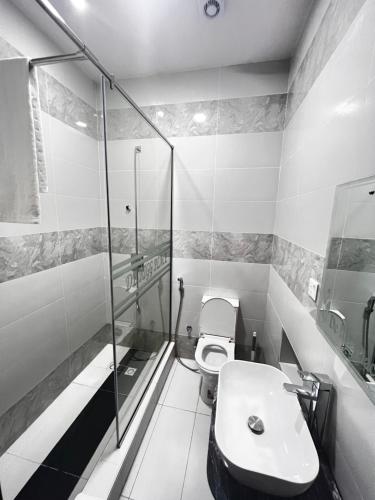 uma casa de banho com um WC e uma cabina de duche em vidro. em De Rigg Place Embassy em Lagos