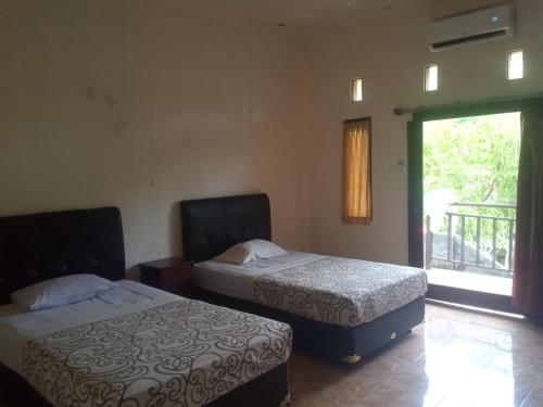 two beds sitting in a room with a window at Belong Bunter Homestay in Uluwatu