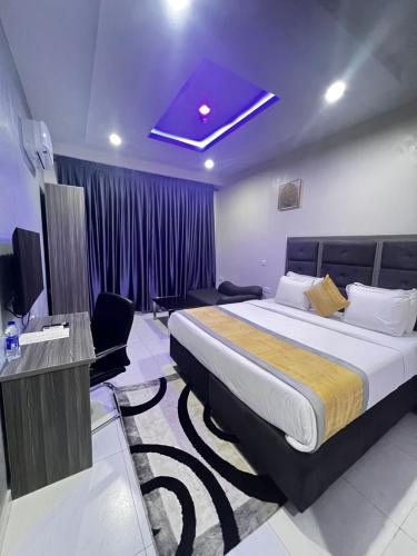 ein Hotelzimmer mit einem großen Bett und einem TV in der Unterkunft De Rigg Place Embassy in Lagos