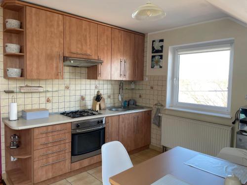 a kitchen with wooden cabinets and a table and a window at Noclegi Nad Małym Jeziorakiem in Iława