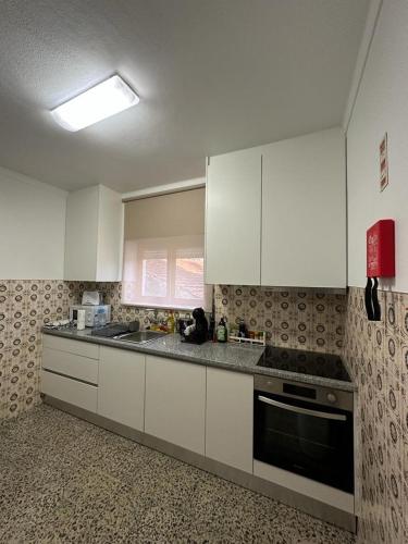 a kitchen with white cabinets and a stove top oven at CASA SOPHIE - Alojamento - Casa de Férias Completa in Ancião