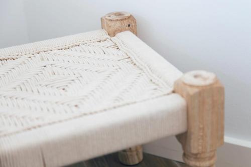 a white bench with wooden stools sitting next to a wall at Casa Biota in Sagres
