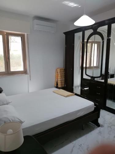 Un dormitorio con una cama blanca y un espejo. en A casa di nonna Giovanna, en Vasto
