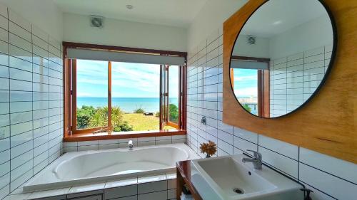 y baño con bañera, espejo y lavabo. en The Beach House Raumati, en Paraparaumu
