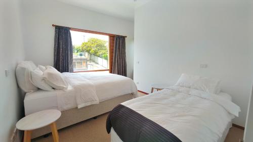 um quarto com 2 camas e uma janela em The Beach House Raumati em Paraparaumu