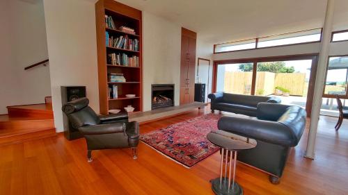 uma sala de estar com mobiliário de couro e uma lareira em The Beach House Raumati em Paraparaumu