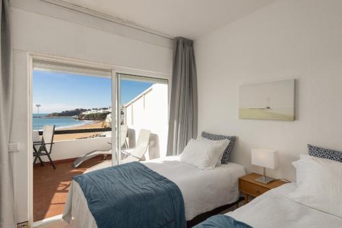 sypialnia z 2 łóżkami i widokiem na ocean w obiekcie Apartamentos Pescadores w Albufeirze