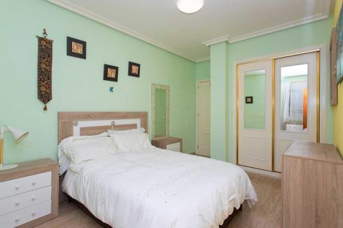 1 dormitorio con cama blanca y paredes verdes en CH La Paz Los Montesinos, en Los Montesinos