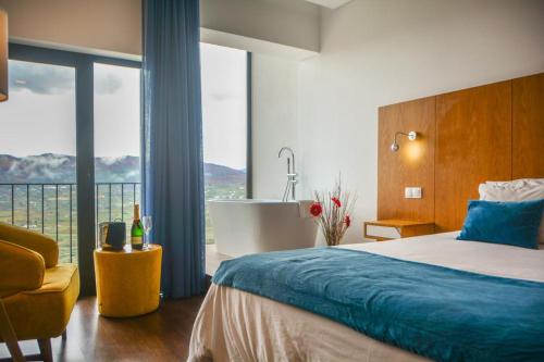 a bedroom with a bed and a bathroom with a tub at Belmonte Sinai Hotel in Belmonte